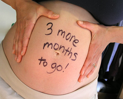a 6 month pregnant belly with the words three months to go written on it