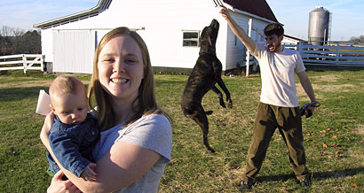 Allison Davis holds Trey as Buster does tricks in the background